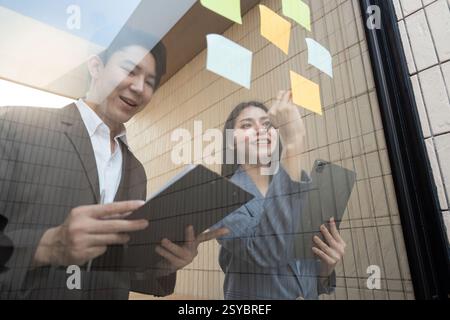 Professionisti aziendali che collaborano all'analisi finanziaria utilizzando tablet e appunti. Foto Stock
