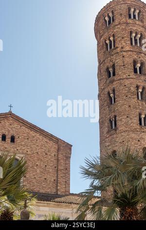 Fotografia di una storica chiesa in mattoni caratterizzata da un'elegante torre sotto un cielo azzurro, circondata da palme, che evoca un'architettura tranquilla Foto Stock