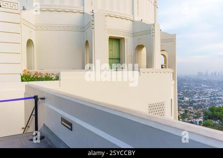 Los Angeles, California - 14 dicembre 2024: Vista ravvicinata dell'architettura dell'Osservatorio Griffith con fiori in fiore e lo skyline di Los Angeles nel Foto Stock