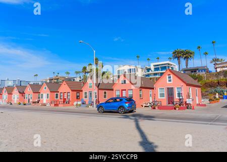 Oceanside, California - 27 dicembre 2024: Pittoreschi cottage sulla spiaggia rosa con un veicolo di passaggio lungo la spiaggia sabbiosa di Oceanside. Foto Stock