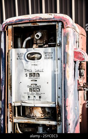 Una vecchia stazione di servizio con un cartello con scritto "questa vendita". La stazione è arrugginita e ha qualche buco Foto Stock