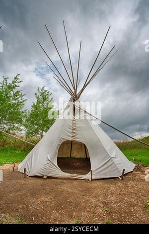 Teepee è in piedi in un campo. Il tepee è bianco e ha un tetto appuntito Foto Stock