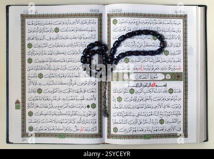 Una copia aperta del testo sacro dell'Islam Corano romanizzò anche Corano o Corano con perline di preghiera Misbaha nere spesso usate dai musulmani per il tasbih, la recitazione delle preghiere, il dhikr, così come per glorificare Allah Foto Stock