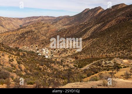 Una piccola strada di passaggio con vedute panoramiche dei tradizionali villaggi berberi si snoda attraverso le montagne dell'alto Atlante vicino a Timkit, Souss-massa, Marocco. Foto Stock