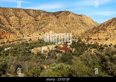 Una piccola strada di passaggio con vedute panoramiche dei tradizionali villaggi berberi si snoda attraverso le montagne dell'alto Atlante vicino a Timkit, Souss-massa, Marocco. Foto Stock