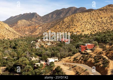 Una piccola strada di passaggio con vedute panoramiche dei tradizionali villaggi berberi si snoda attraverso le montagne dell'alto Atlante vicino a Timkit, Souss-massa, Marocco. Foto Stock