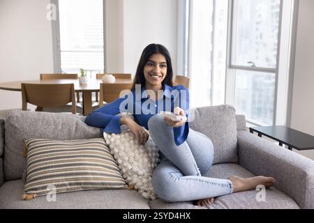Giovane donna che passa del tempo libero a guardare la TV a casa Foto Stock