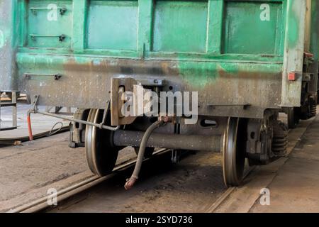 Il vagone ferroviario verde è in fase di restauro sui binari all'interno dell'officina ferroviaria, mostrando la sua costruzione di ruote. Foto Stock