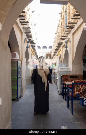Uomini arabi che camminano nel souq waqif vista posteriore. Il Souq Waqif è un souq di Doha, noto per la vendita di gar tradizionali Foto Stock