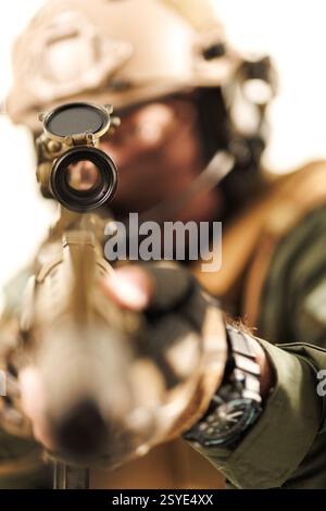 Soldato concentrato vestito con uniforme militare, puntando con precisione attraverso un fucile dotato di oscilloscopio. Dimostra concetti di addestramento militare, combattimento Foto Stock