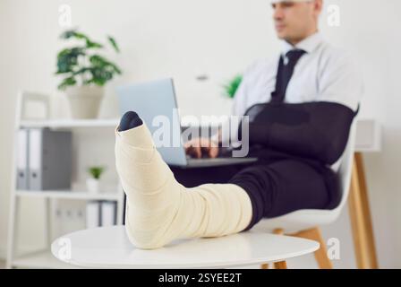Riabilitazione del lavoratore in ufficio dopo una gamba grave, un trauma al braccio, lesioni da incidente fisico, lavoro Foto Stock