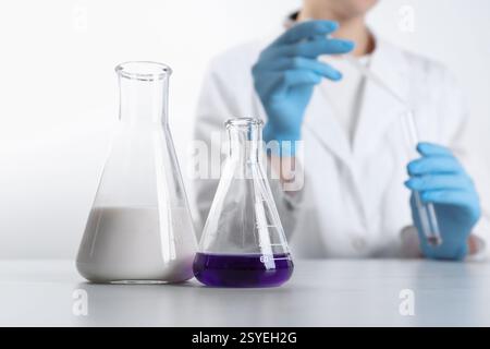Analisi di laboratorio. Scienziato che lavora con la vetreria su un tavolo in marmo bianco, focalizza l'attenzione sulle fiasche Foto Stock