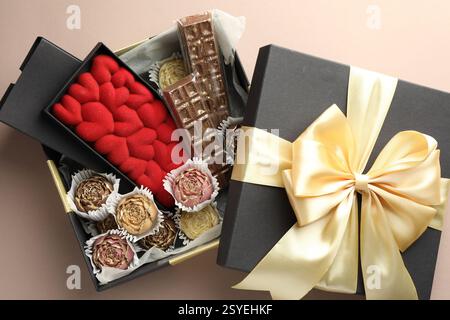 Diversi deliziosi dolci al cioccolato in scatola su sfondo beige, vista dall'alto Foto Stock