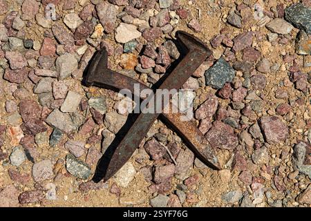 Una coppia incrociata di vecchie punte della ferrovia giace sul terreno vicino ai binari della ferrovia. Foto Stock