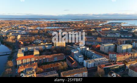 Una vista aerea panoramica di Karlstad, Svezia, con una calda luce del tramonto che illumina il paesaggio cittadino, gli edifici residenziali e il lungomare, creando un'atmosfera tranquilla e pittoresca. Foto Stock