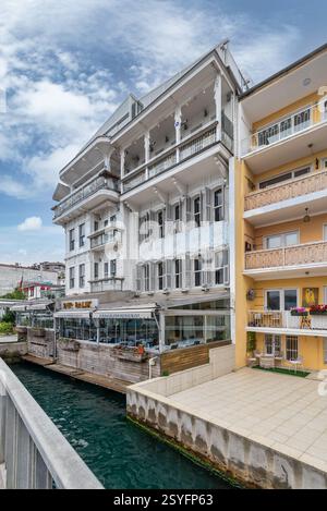Istanbul, Turchia - 12 maggio 2023: Edifici residenziali tradizionali in legno vicino a uno stretto canale d'acqua vicino allo stretto del Bosforo ad Arnavutkoy, nel quartiere di Besiktas, in una giornata di sole primaverili Foto Stock