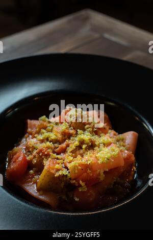 Un primo piano di pasta paccheri gourmet servita con un ricco sugo di pomodoro, verdure arrostite e un condimento di croccanti pangrattati, presentati elegantemente Foto Stock