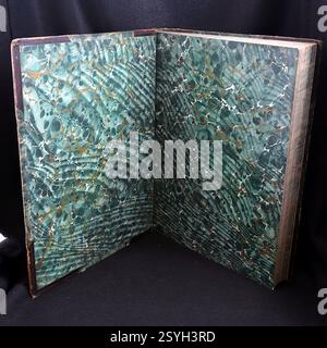 Carta marmorizzata all'interno della copertina anteriore di un vecchio libro in pelle. L'effetto marmo verde viene stampato sulla pagina incollata sulla copertina e sull'estremità anteriore libera Foto Stock