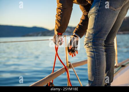 Il giovane capitano gestisce e controlla una barca a vela durante un viaggio via mare nel periodo invernale in Montenegro Foto Stock