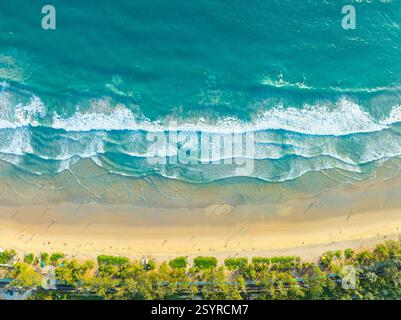 Una splendida vista aerea che cattura le onde turchesi dell'oceano che si tuffano dolcemente su una spiaggia di sabbia dorata, con persone sparsi lungo la riva. Il vibrano Foto Stock