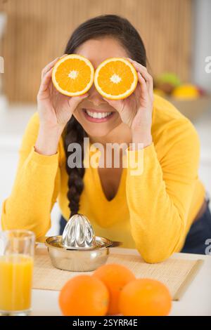 donna che posa con una fetta d'arancia sul viso Foto Stock