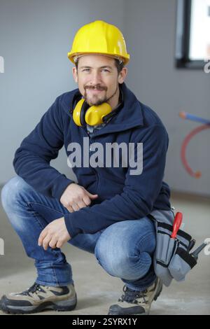 giovane e amichevole commerciante accovacciato a terra Foto Stock