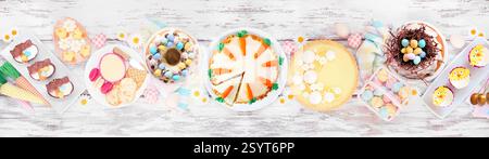 Tavola dei dessert di Pasqua o di primavera. Vista dall'alto su uno sfondo bianco per striscioni in legno. Crostata al limone, cupcake, uovo di Pasqua e torte di carote e un asso Foto Stock