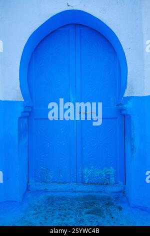 doppia porta ad arco simmetrica, blu brillante, adagiata su una parete bianca e blu a contrasto Foto Stock