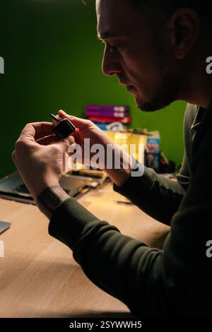 Immagine verticale laterale di un tecnico specializzato che ripara la batteria dello smartwatch, utilizzando pinzette fini per estrarre e sostituire con precisione i componenti Foto Stock