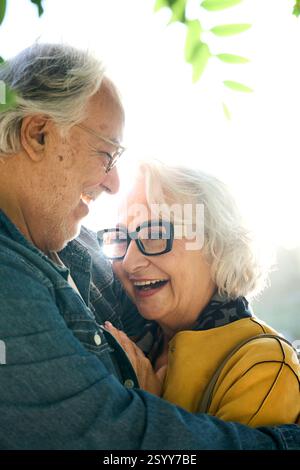 Felice coppia di anziani che abbraccia nel parco vicino al lago Foto Stock