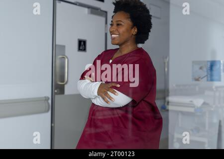 Felice afro-americano medico che indossa scrub in corridoio all'ospedale Foto Stock