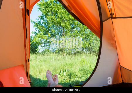 Uomo che riposa all'interno della tenda arancione Foto Stock