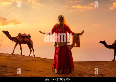 Donna Rajasthani che balla nel deserto al tramonto Foto Stock
