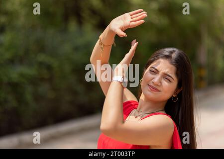 Donna che si copre la faccia dal sole con la mano nel parco Foto Stock