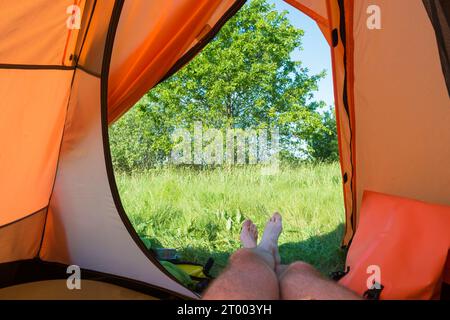 Uomo che riposa all'interno della tenda arancione Foto Stock