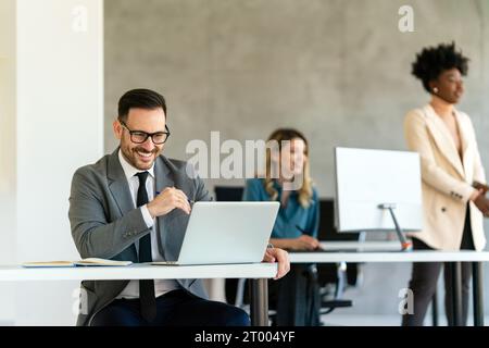 Uomini d'affari con colleghi commercianti in ufficio che monitorano i dati delle scorte sullo schermo analizzando il flusso dei prezzi Foto Stock