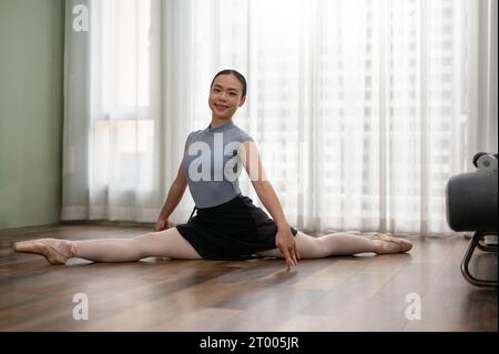 Giovane ballerina graziosa, ballerina di balletto. Donna che fa esercizi di stretching sul pavimento a casa. Donna che fa esercizio fisico a casa. Foto Stock
