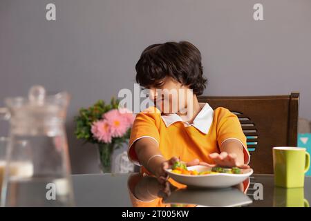 Ritratto di un ragazzo infelice che mangia broccoli Foto Stock