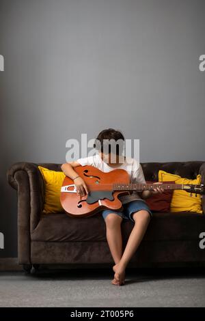 Ragazzo che suona la chitarra in salotto Foto Stock