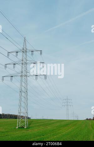 ENERGIA ECOLOGICA. Linee di alimentazione ad alta tensione che attraversano un campo verde. Trasmissione di energia elettrica mediante supporti Foto Stock