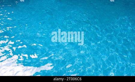 Acqua della piscina astratta. I caustici sul fondo della piscina si riversano e scorrono con onde che fanno da sfondo alla piscina blu Foto Stock