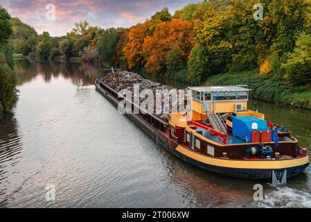 Settore dei trasporti. La chiatta della nave trasporta rottami metallici e sabbia con ghiaia. La chiatta caricata con rottami metallici si trova sulla strada Foto Stock