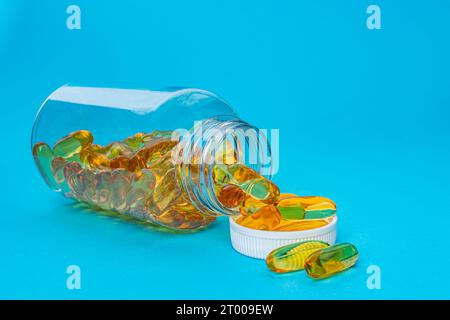 Capsule di gel omega-3 per fegato di merluzzo bianco, pillole di gel gialle in flacone trasparente su sfondo blu. Foto di alta qualità Foto Stock