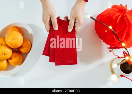 Donna asiatica che dà busta rossa per le celebrazioni del Capodanno lunare. Tenere la mano nella confezione rossa Foto Stock