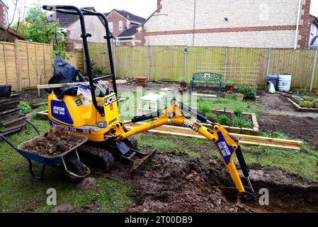 Mini scavatrice parcheggiata in un giardino utilizzato per scavare terreno per costruire una serra, Chard, Somerset, Regno Unito, Europa. Foto Stock