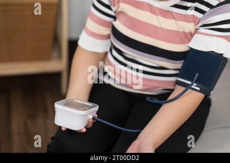Controllo automatico della pressione sanguigna e della frequenza cardiaca da parte della donna in sovrappeso Plus size. Foto Stock