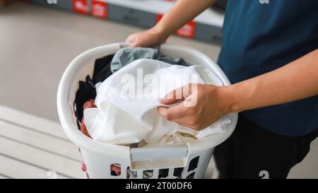 Uomo che fa lavare tenendo cesto con la lavanderia sporca della lavatrice nel negozio pubblico. concetto di lavanderia Foto Stock