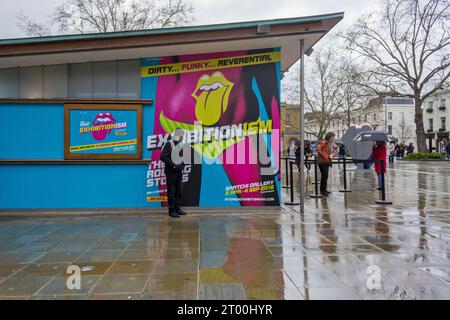 Uomo al riparo dalla pioggia da un poster che pubblicizza la mostra esibizionistica di Rolling Stones 2016 alla Saatchi Gallery, Londra, Regno Unito Foto Stock