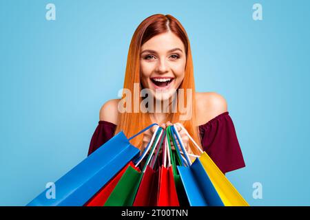 Black friday ragazza dai capelli rossi ride tenendo multicolori vivaci borse shopping isolato su sfondo giallo Foto Stock