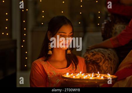 Ritratto di una giovane donna che tiene in mano un piatto di lampade a candela in occasione di Diwali Foto Stock